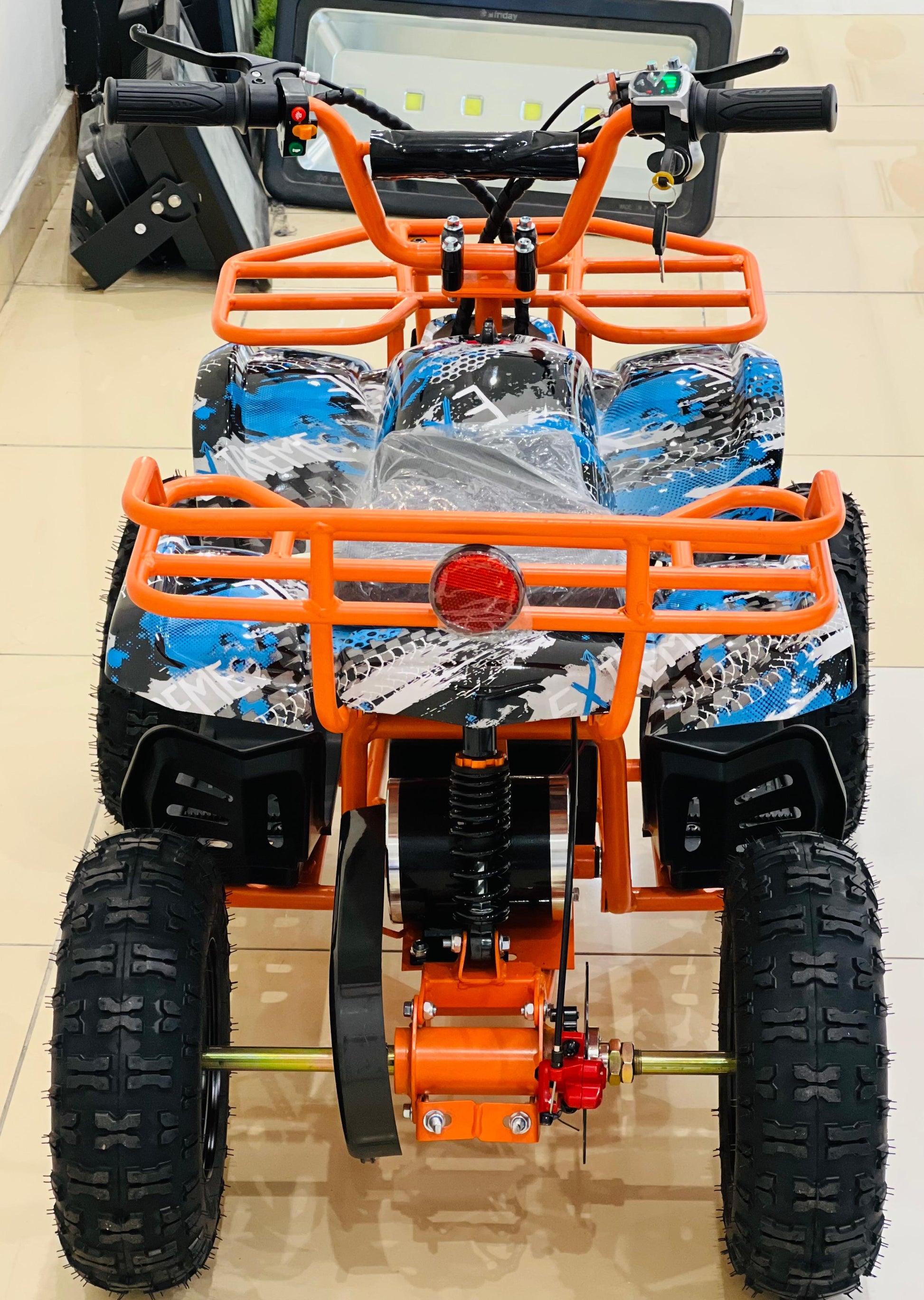 Kid riding a small electric quad bike with safety gear outdoors.