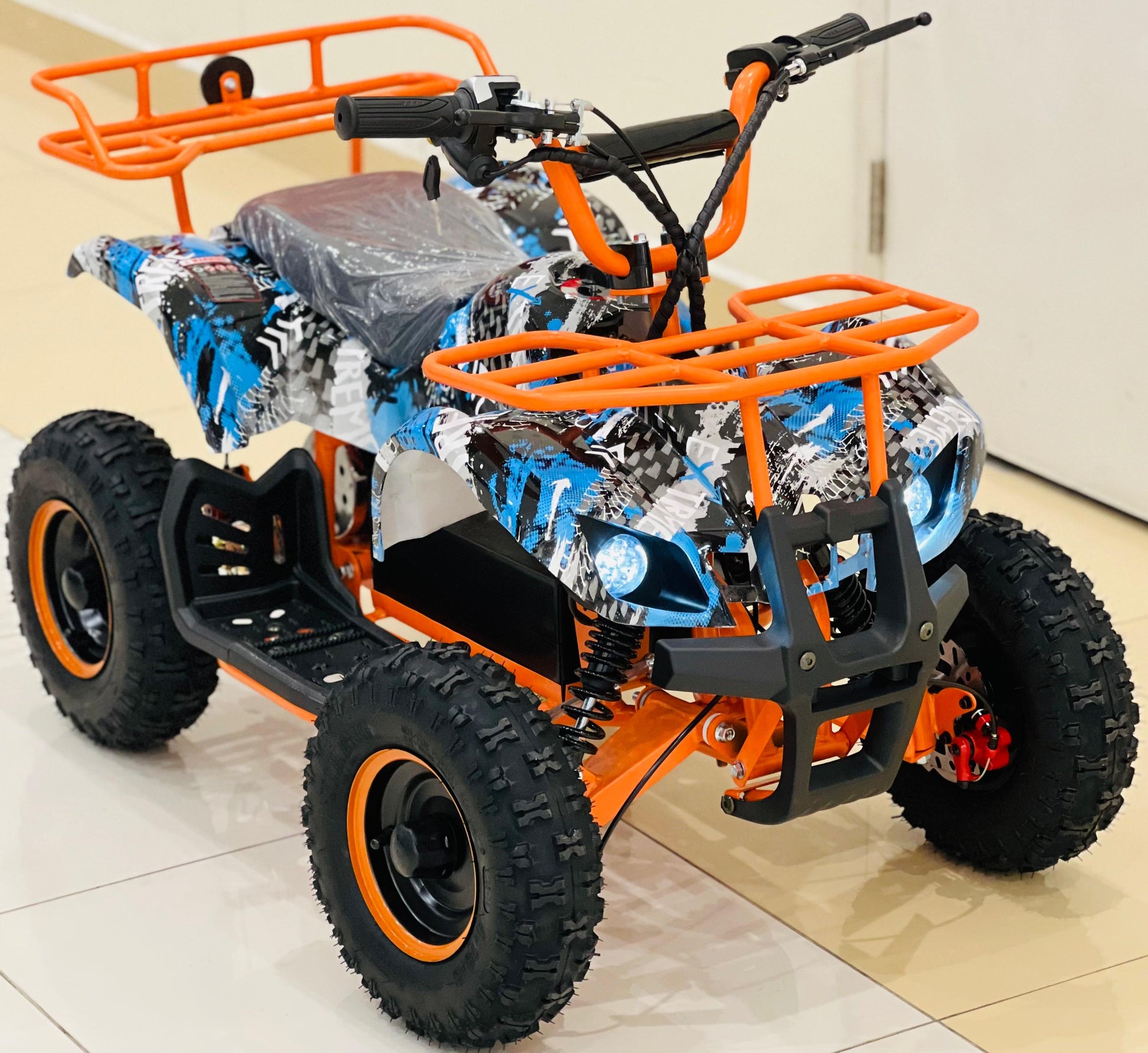 Young child driving a kids' electric quad bike across a grassy yard.